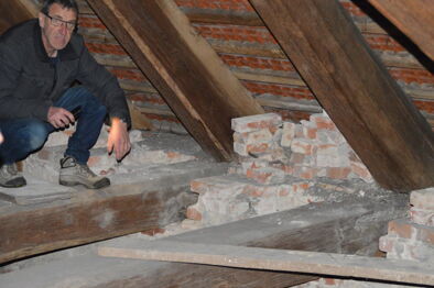 Ingo Dreger zeigt die schadhaften Köpfe der Dachbalken und Mauerziegel